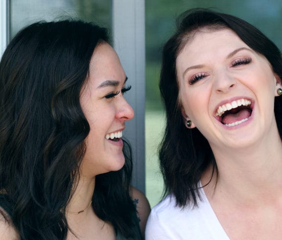 Two young women laughing with their mouths open